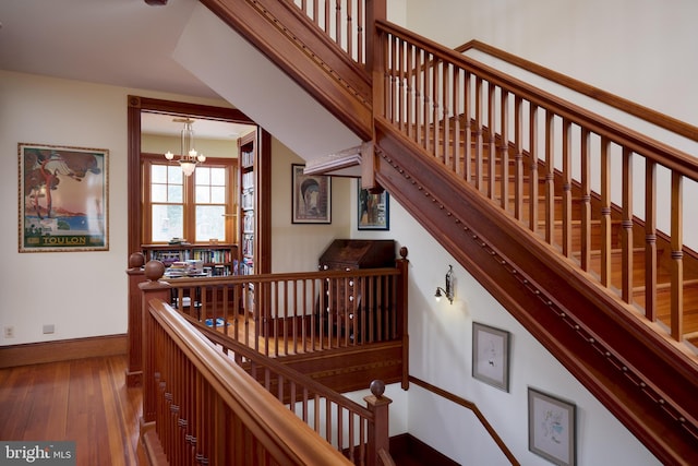 stairs featuring hardwood / wood-style floors and an inviting chandelier