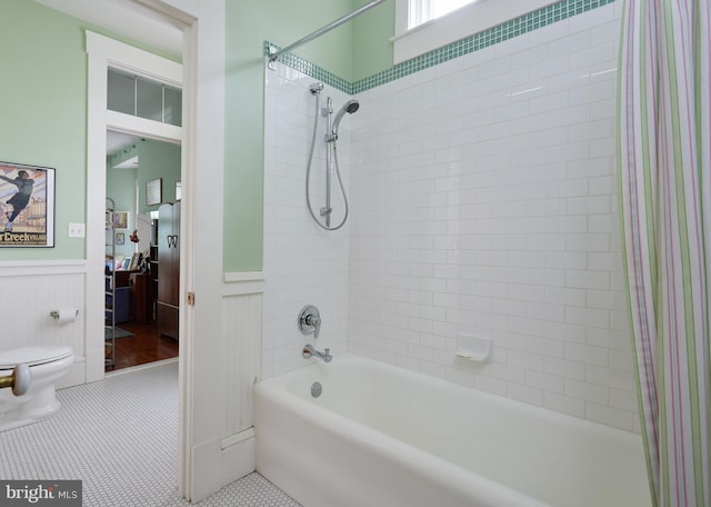 bathroom with tiled shower / bath combo, toilet, and tile patterned flooring