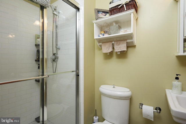 bathroom featuring toilet and a shower with door