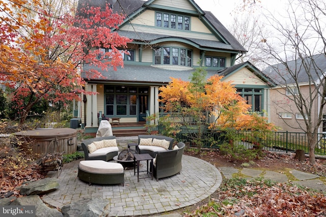 back of property featuring cooling unit, a hot tub, a patio, and a fire pit