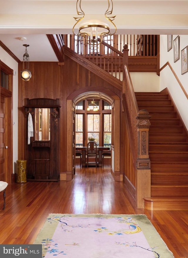 foyer entrance featuring dark hardwood / wood-style floors, wooden walls, and an inviting chandelier