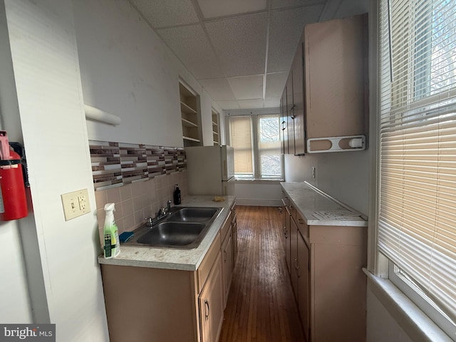 kitchen featuring a drop ceiling, dark wood-type flooring, white refrigerator, sink, and tasteful backsplash