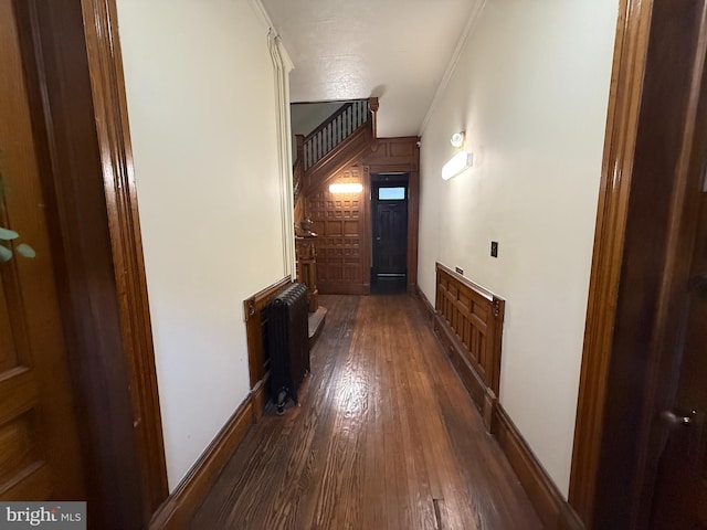 corridor featuring radiator heating unit, dark hardwood / wood-style flooring, and ornamental molding