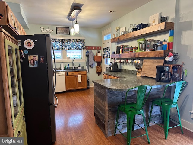 kitchen with a breakfast bar, white dishwasher, decorative light fixtures, dark hardwood / wood-style flooring, and kitchen peninsula