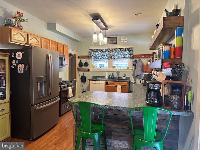 kitchen featuring sink, stainless steel appliances, an inviting chandelier, light hardwood / wood-style floors, and decorative light fixtures