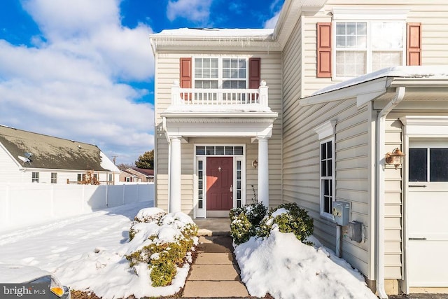 snow covered property entrance with a balcony