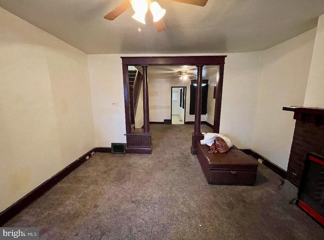 living room featuring decorative columns, ceiling fan, and dark colored carpet