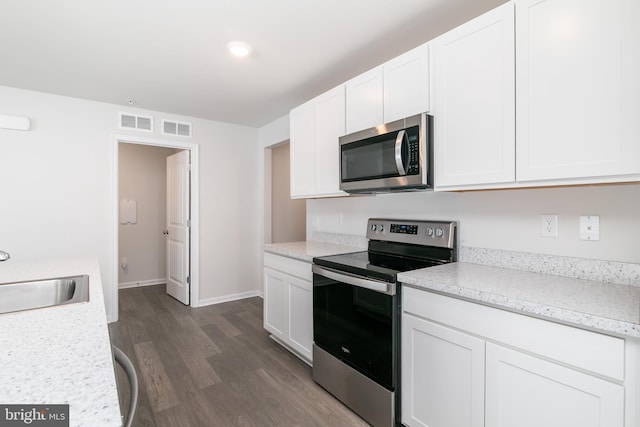 kitchen featuring appliances with stainless steel finishes, white cabinetry, dark hardwood / wood-style floors, and sink