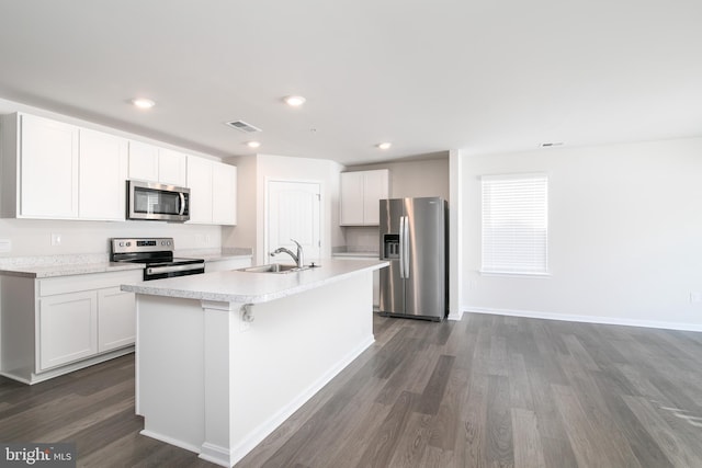 kitchen with stainless steel appliances, white cabinetry, sink, and an island with sink