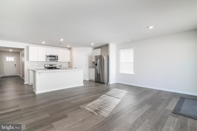 kitchen with white cabinetry, dark wood-type flooring, an island with sink, and appliances with stainless steel finishes