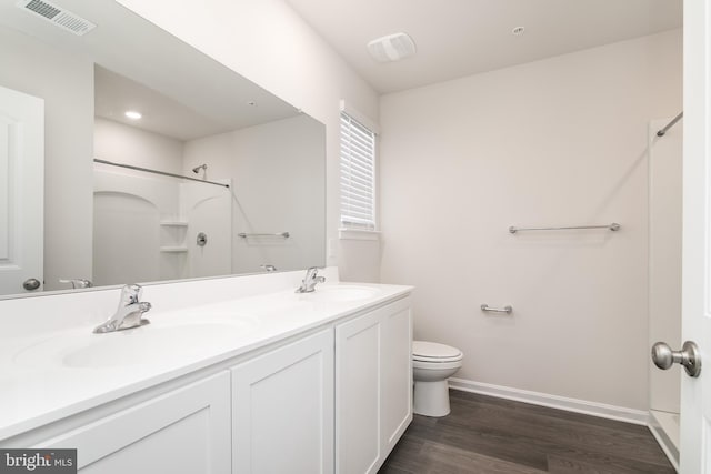 bathroom with toilet, hardwood / wood-style flooring, a shower, and vanity