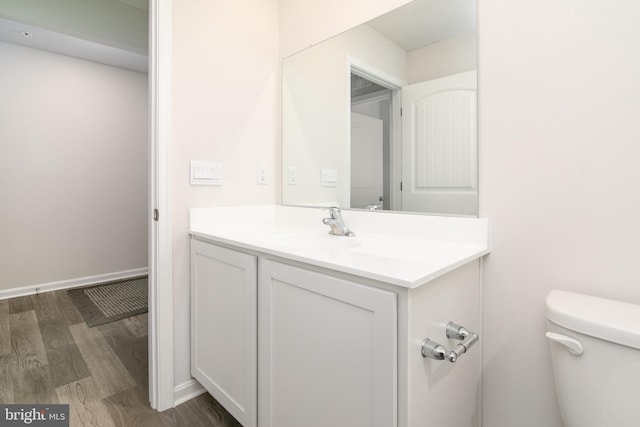 bathroom with toilet, wood-type flooring, and vanity