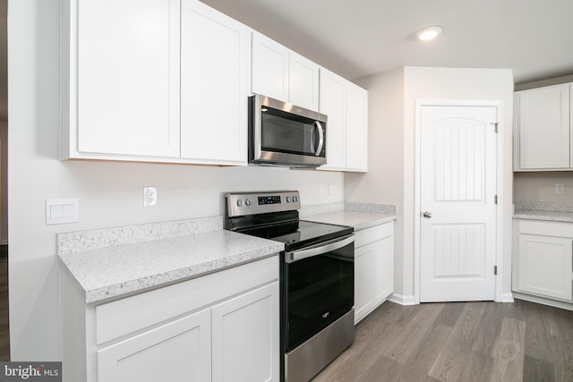 kitchen featuring hardwood / wood-style flooring, appliances with stainless steel finishes, and white cabinetry