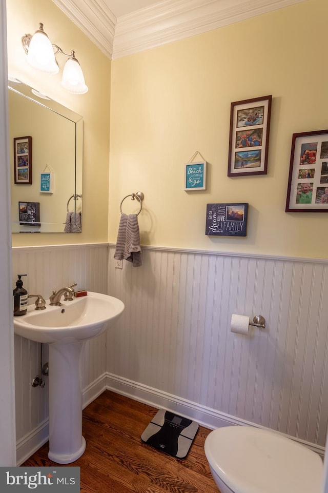 bathroom featuring hardwood / wood-style floors, crown molding, and toilet