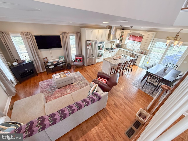 living room featuring an inviting chandelier, a wealth of natural light, and light hardwood / wood-style flooring