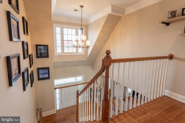 staircase with a chandelier, hardwood / wood-style flooring, and ornamental molding