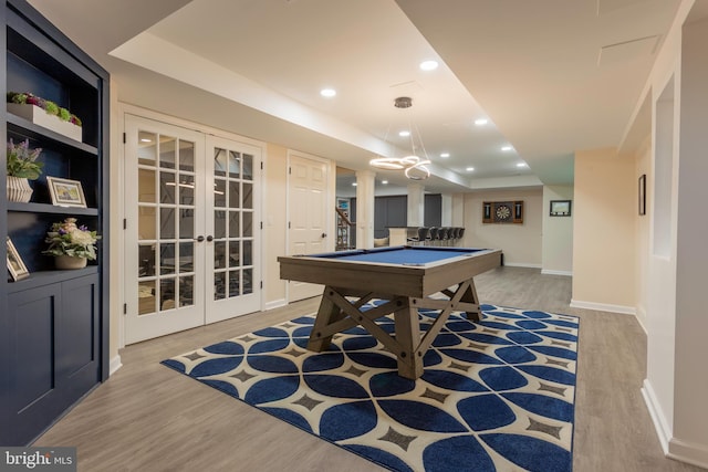 recreation room featuring pool table, light wood-type flooring, french doors, and a tray ceiling