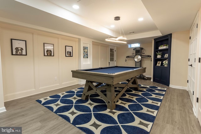 rec room with pool table, a tray ceiling, and wood-type flooring