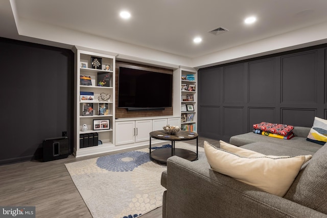 living room featuring light wood-type flooring and built in features