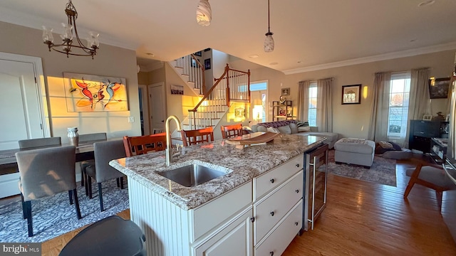 kitchen with an inviting chandelier, an island with sink, white cabinets, decorative light fixtures, and sink