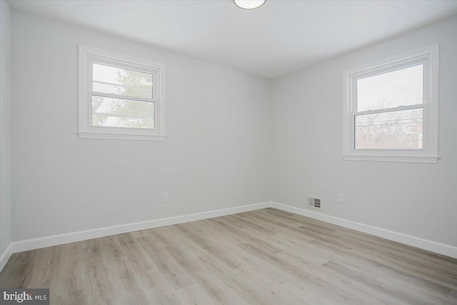 empty room featuring a healthy amount of sunlight and light hardwood / wood-style floors