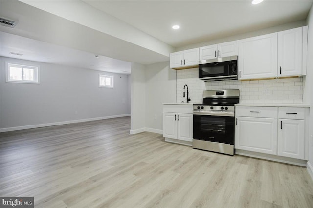 kitchen featuring tasteful backsplash, white cabinets, stainless steel appliances, and light wood-type flooring