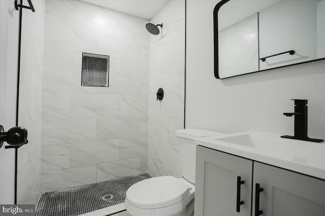 bathroom featuring vanity, toilet, and a tile shower