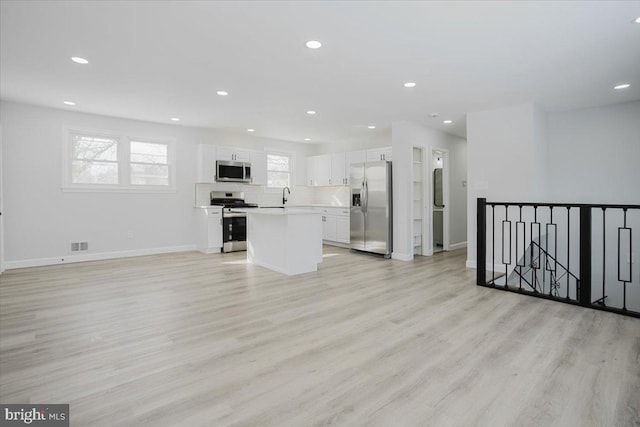 unfurnished living room with light hardwood / wood-style flooring and sink