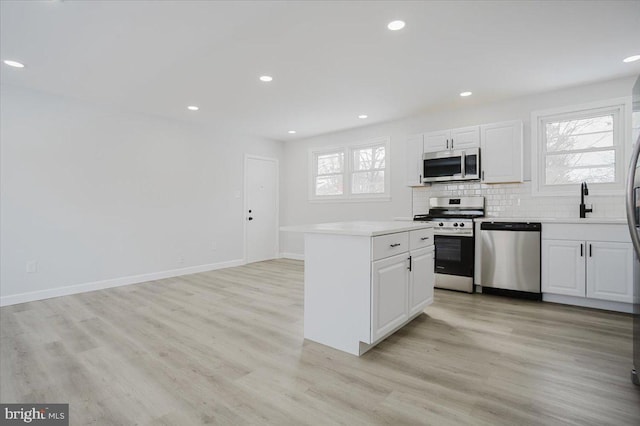 kitchen with stainless steel appliances, white cabinetry, plenty of natural light, and light hardwood / wood-style flooring