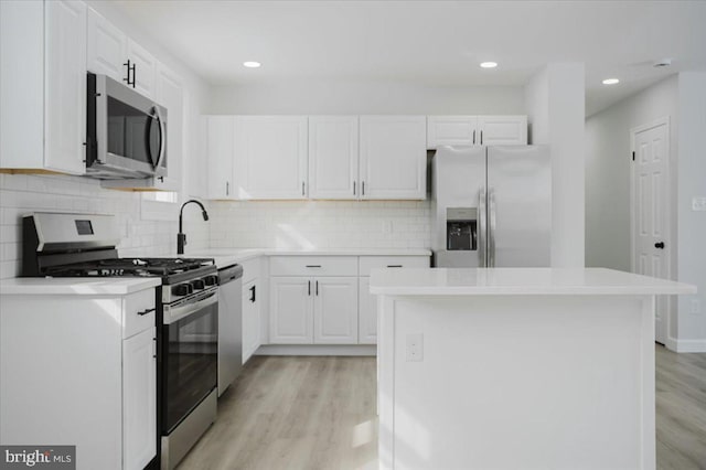 kitchen with a center island, light hardwood / wood-style flooring, tasteful backsplash, white cabinetry, and stainless steel appliances