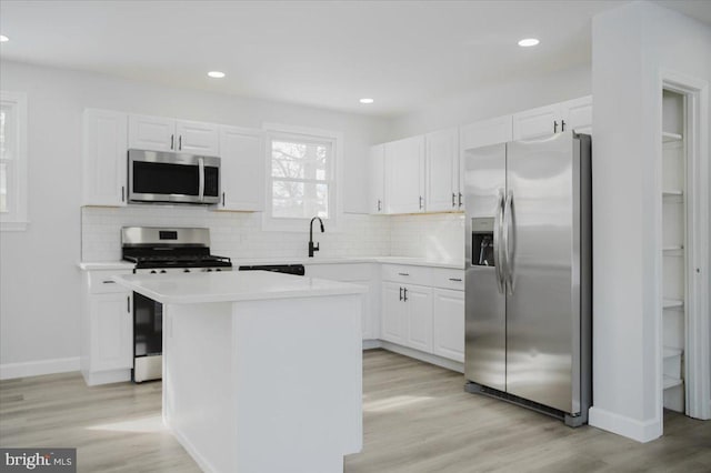 kitchen featuring sink, stainless steel appliances, a kitchen island, light hardwood / wood-style floors, and white cabinets