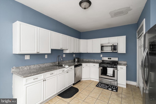 kitchen with light tile patterned floors, stainless steel appliances, sink, and white cabinets