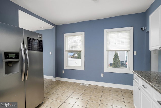 kitchen with white cabinetry, light tile patterned flooring, dark stone countertops, and stainless steel refrigerator with ice dispenser