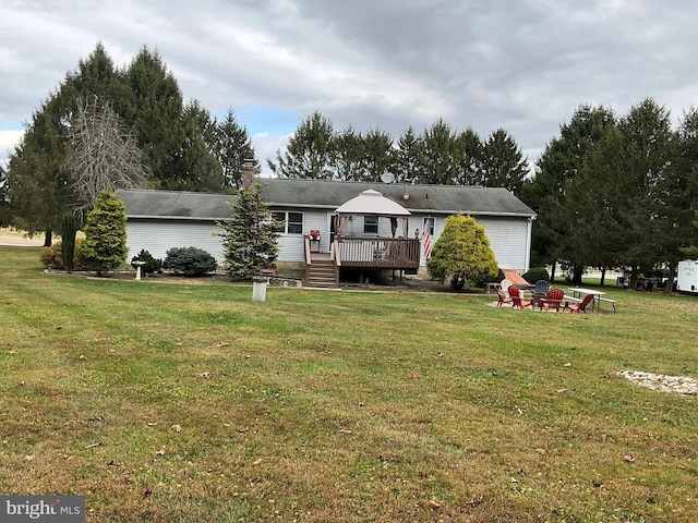 rear view of property featuring a deck, an outdoor fire pit, a yard, and a gazebo