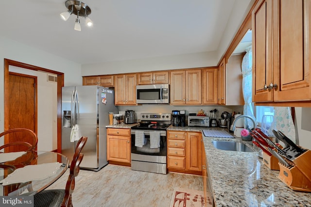 kitchen with light stone countertops, sink, and appliances with stainless steel finishes