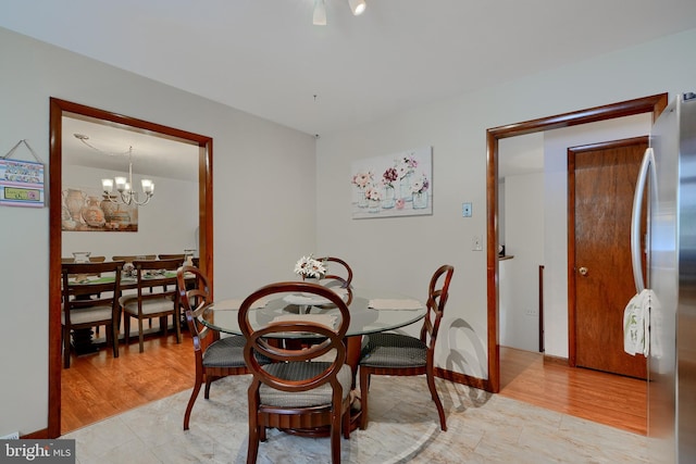 dining space with light hardwood / wood-style floors and a chandelier