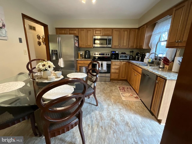 kitchen with light stone counters, sink, and stainless steel appliances