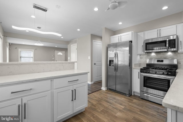 kitchen with pendant lighting, dark hardwood / wood-style flooring, white cabinetry, and appliances with stainless steel finishes