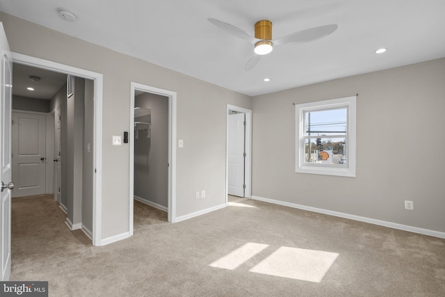 unfurnished bedroom featuring a spacious closet, ceiling fan, and light carpet