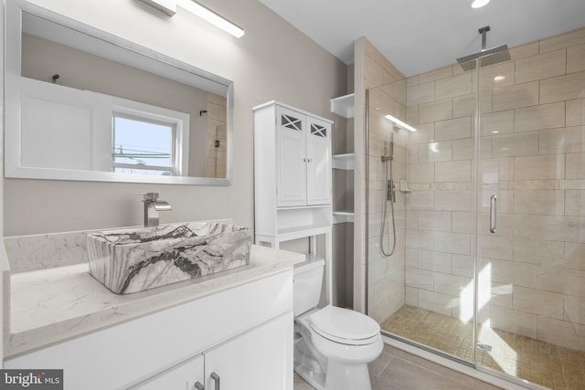 bathroom with tile patterned floors, vanity, toilet, and a shower with door