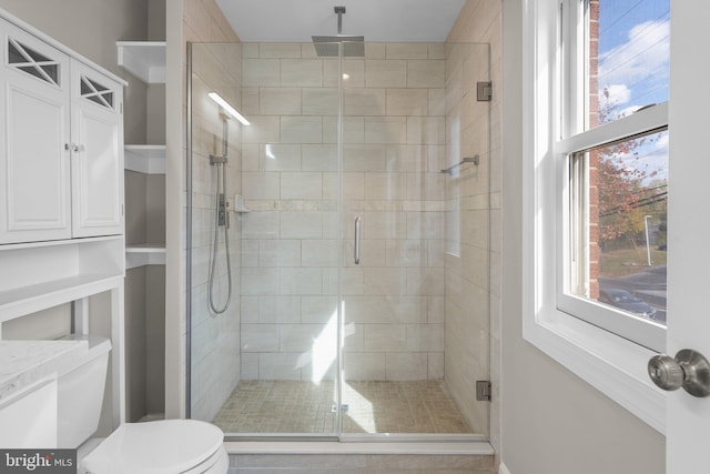 bathroom featuring toilet and a shower with shower door