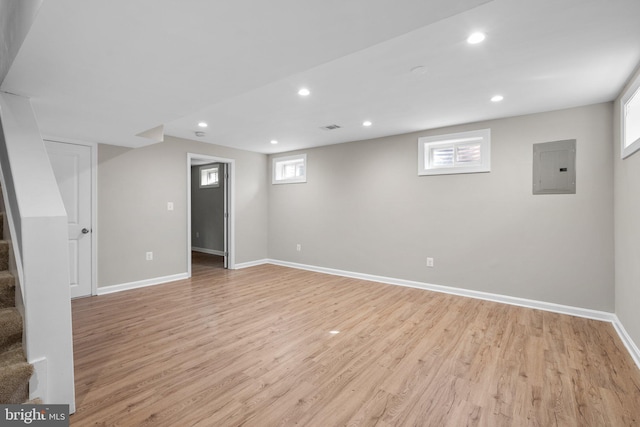 basement with light wood-type flooring and electric panel