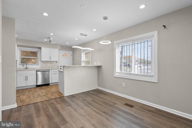 kitchen featuring white cabinetry, dishwasher, kitchen peninsula, wood-type flooring, and decorative light fixtures