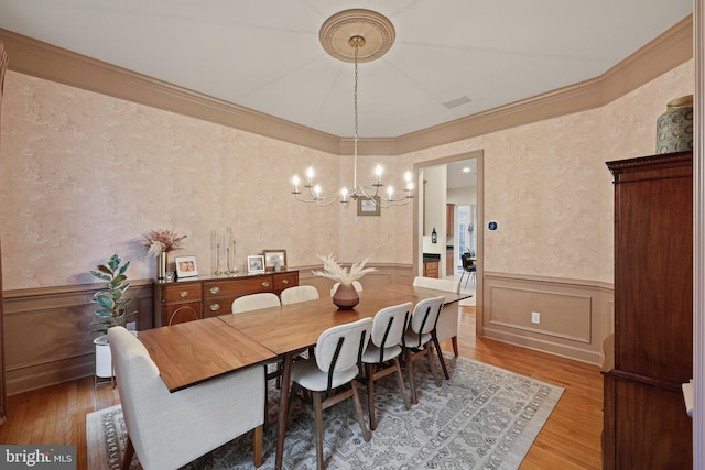 dining room with hardwood / wood-style flooring, crown molding, and an inviting chandelier