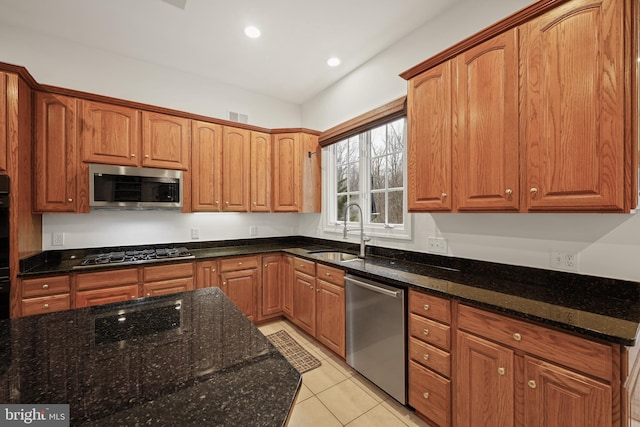 kitchen with stainless steel appliances, sink, dark stone countertops, and light tile patterned floors