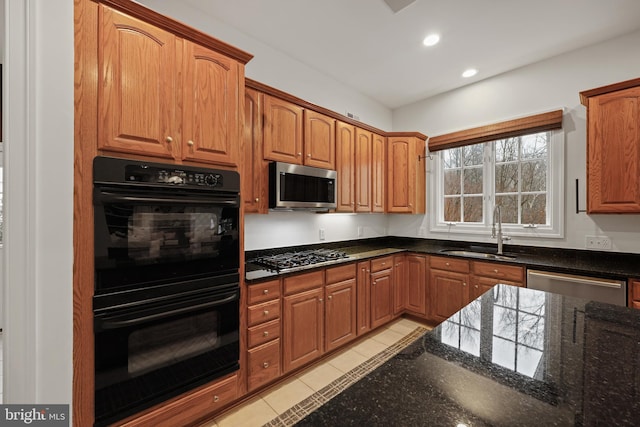 kitchen with dark stone countertops, sink, light tile patterned floors, and appliances with stainless steel finishes