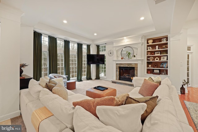 living room with a stone fireplace and built in shelves