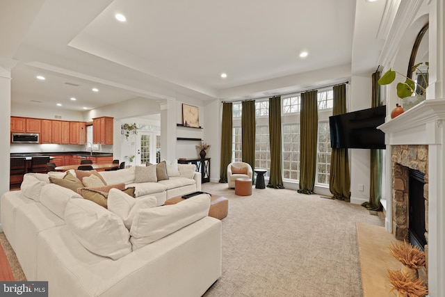 living room featuring decorative columns, a fireplace, sink, and light carpet