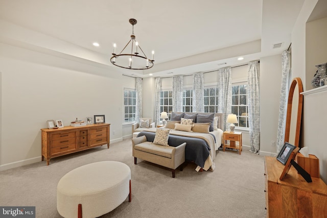 carpeted bedroom featuring multiple windows, a tray ceiling, and a chandelier