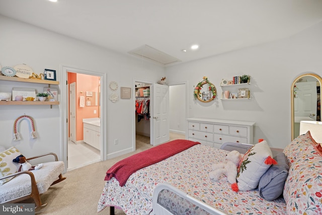 bedroom with a walk in closet, connected bathroom, a closet, and light carpet